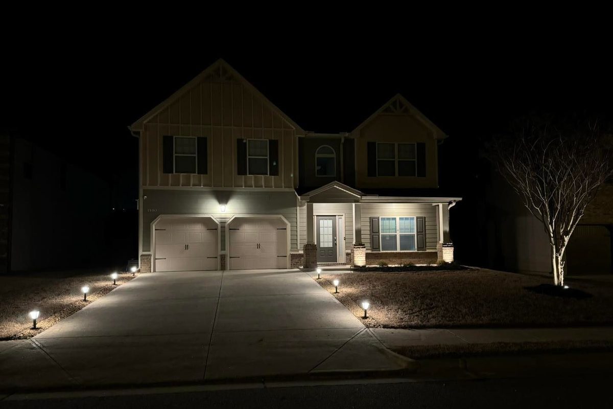 Path lights and uplighting on a two-storey home after dark